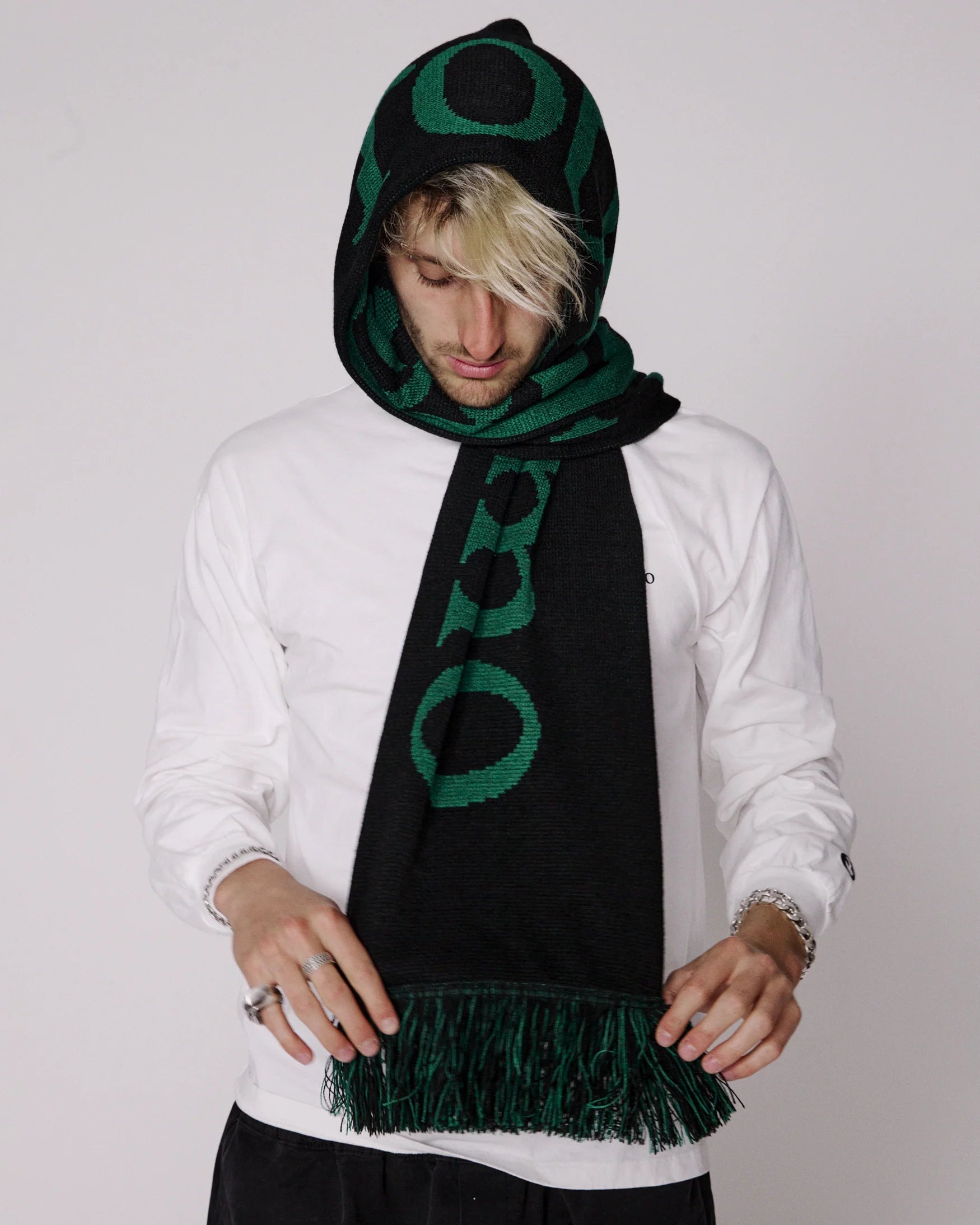 Person wearing a black and green scarf with a pattern on a white background