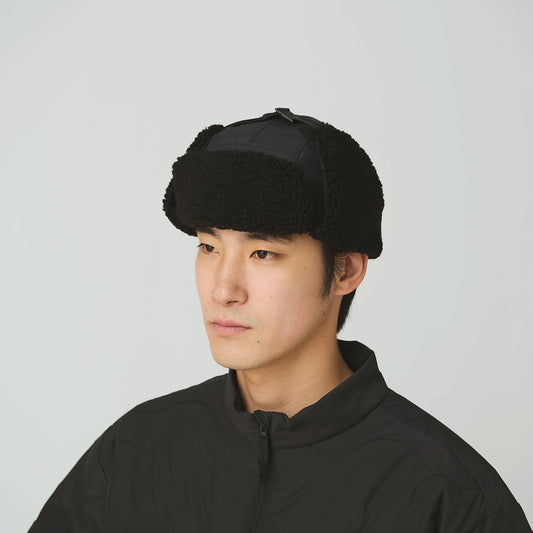 Person wearing a black knit hat against a plain background