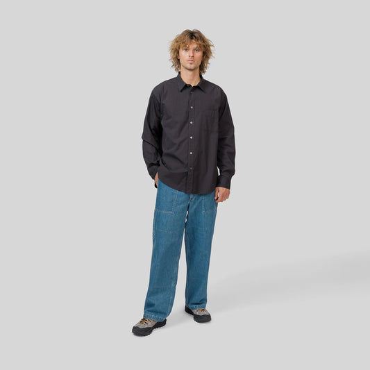 Man wearing a black shirt and blue jeans on a gray background