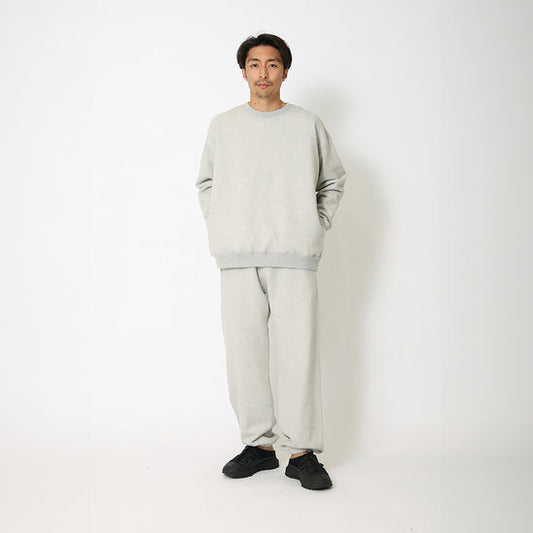 Person wearing a light gray sweatshirt and pants set on a white background