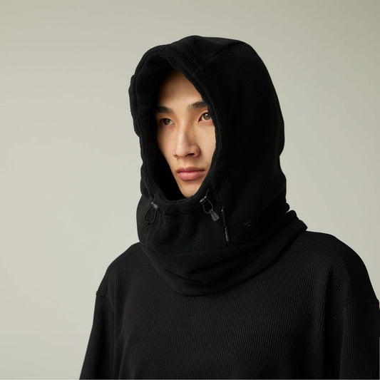 Person wearing a black hooded garment against a plain background