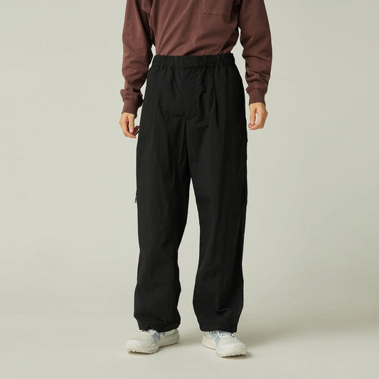 Person wearing a brown sweatshirt and black pants on a plain background