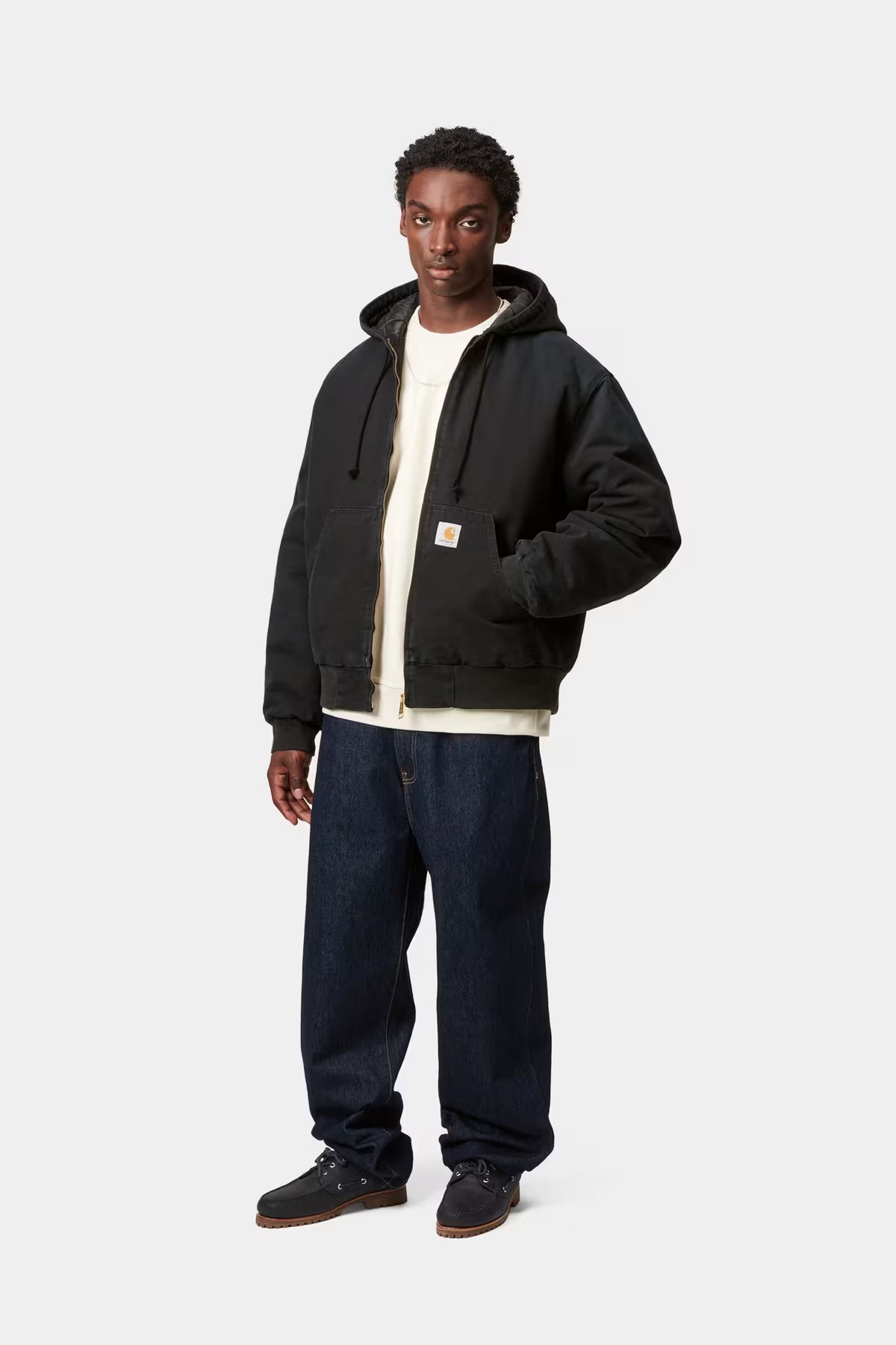 Person wearing a black jacket with a white shirt and dark pants on a white background