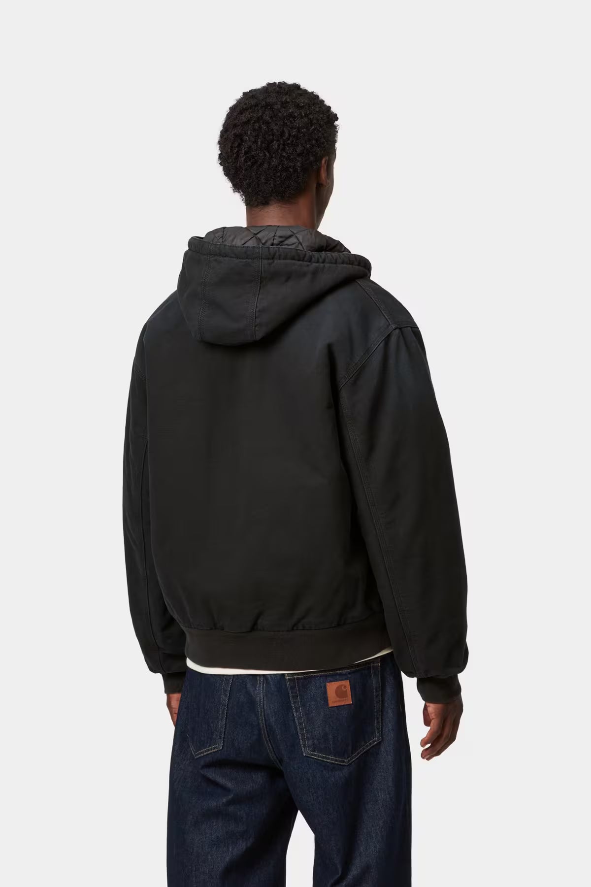 Person wearing a black jacket with a hood on a white background