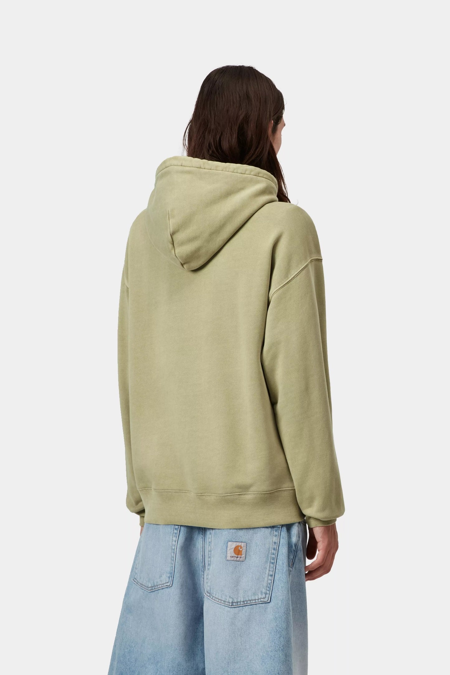 Person wearing a light green hoodie and blue jeans on a white background