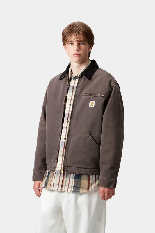 Person wearing a brown jacket with a visible brand logo on a white background