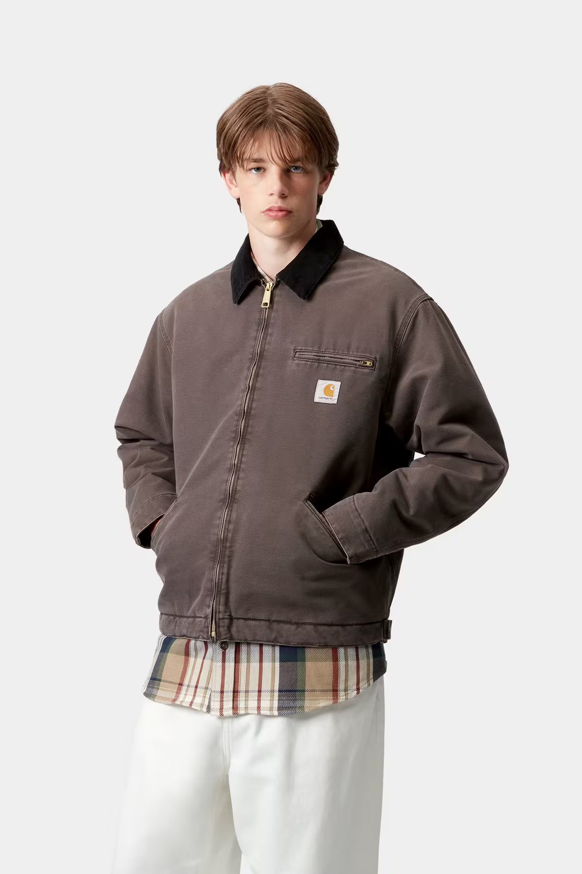 Person wearing a brown jacket with a visible brand logo on a white background