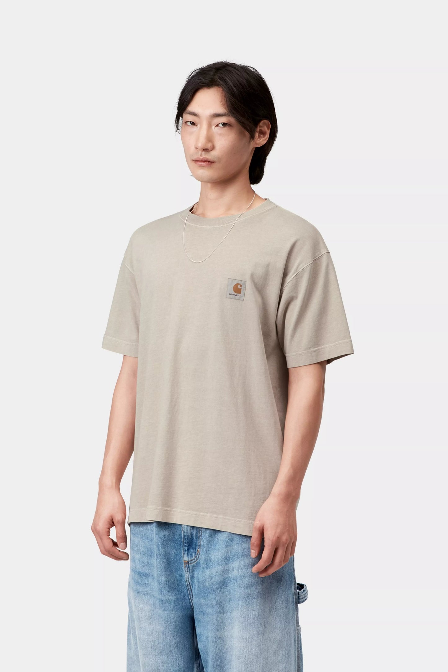 Person wearing a beige t-shirt with a brand logo on a white background