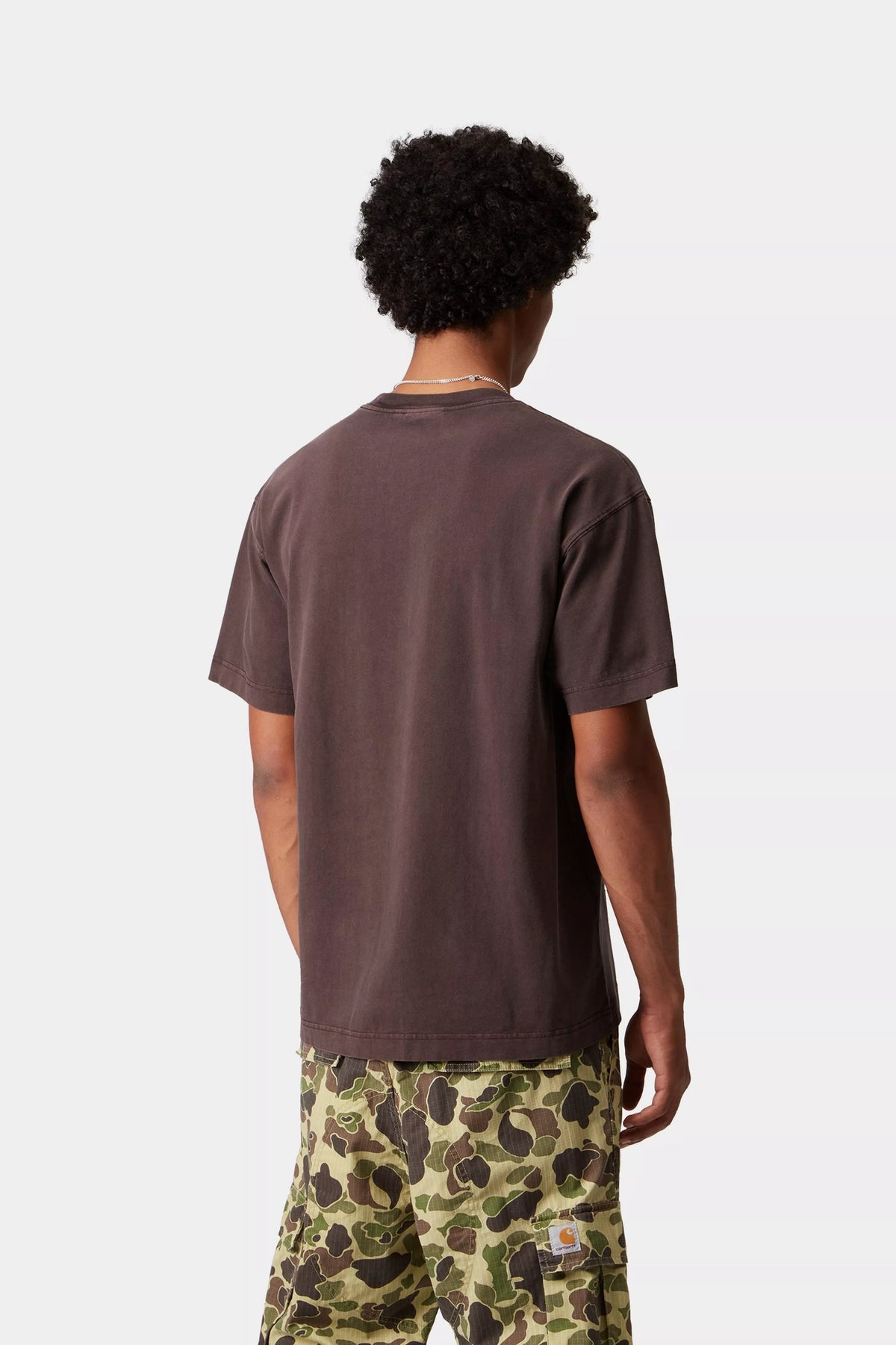 Person wearing a brown t-shirt and camouflage pants on a white background