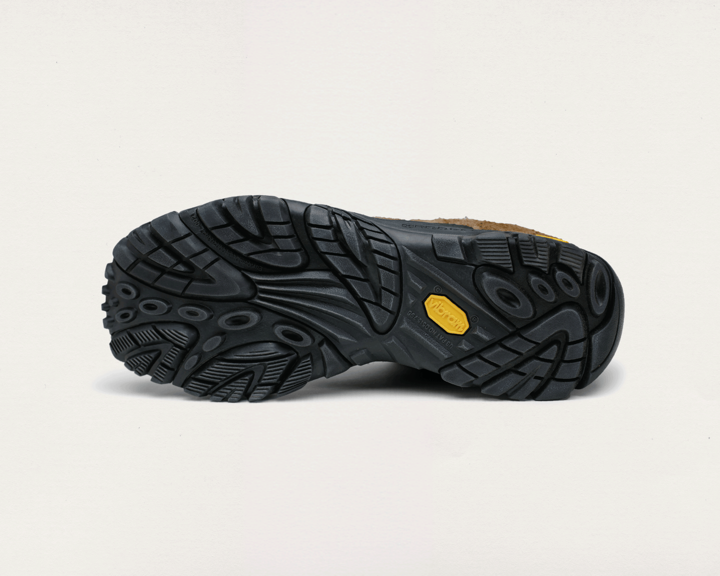 Close-up of a black shoe sole with a yellow label on a light gray background