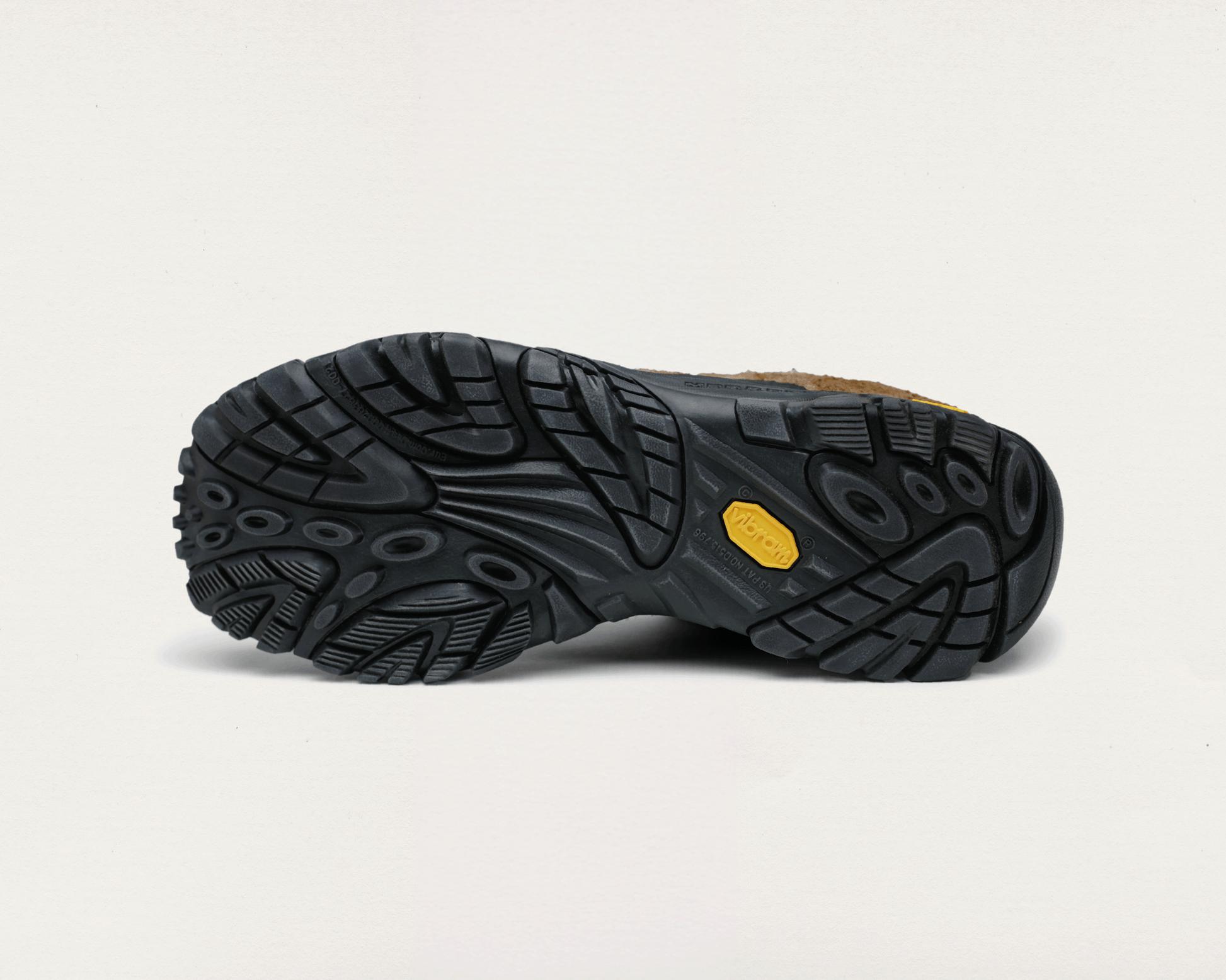 Close-up of a black shoe sole with a yellow label on a light gray background