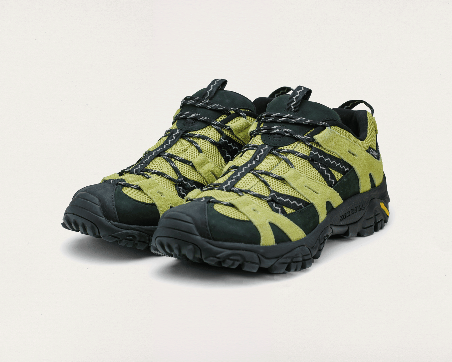 Pair of green and black hiking shoes on a light gray background