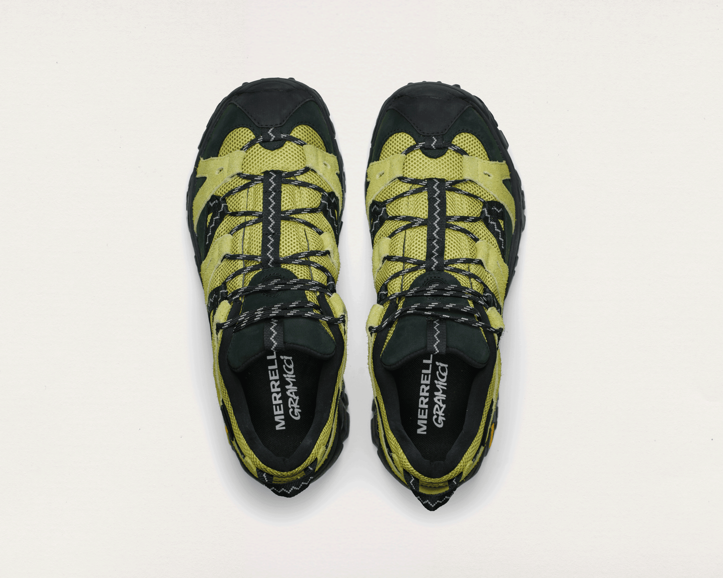 Pair of yellow and black hiking shoes with 'Merrell' branding on a light gray background
