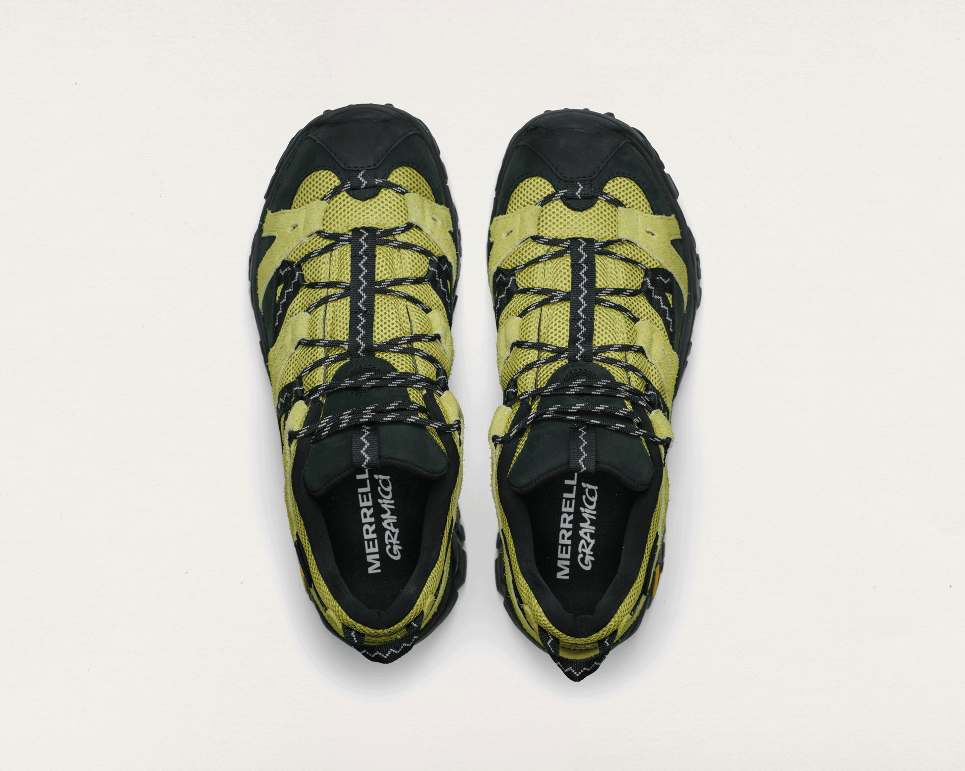 Pair of yellow and black hiking shoes with 'Merrell' branding on a light gray background