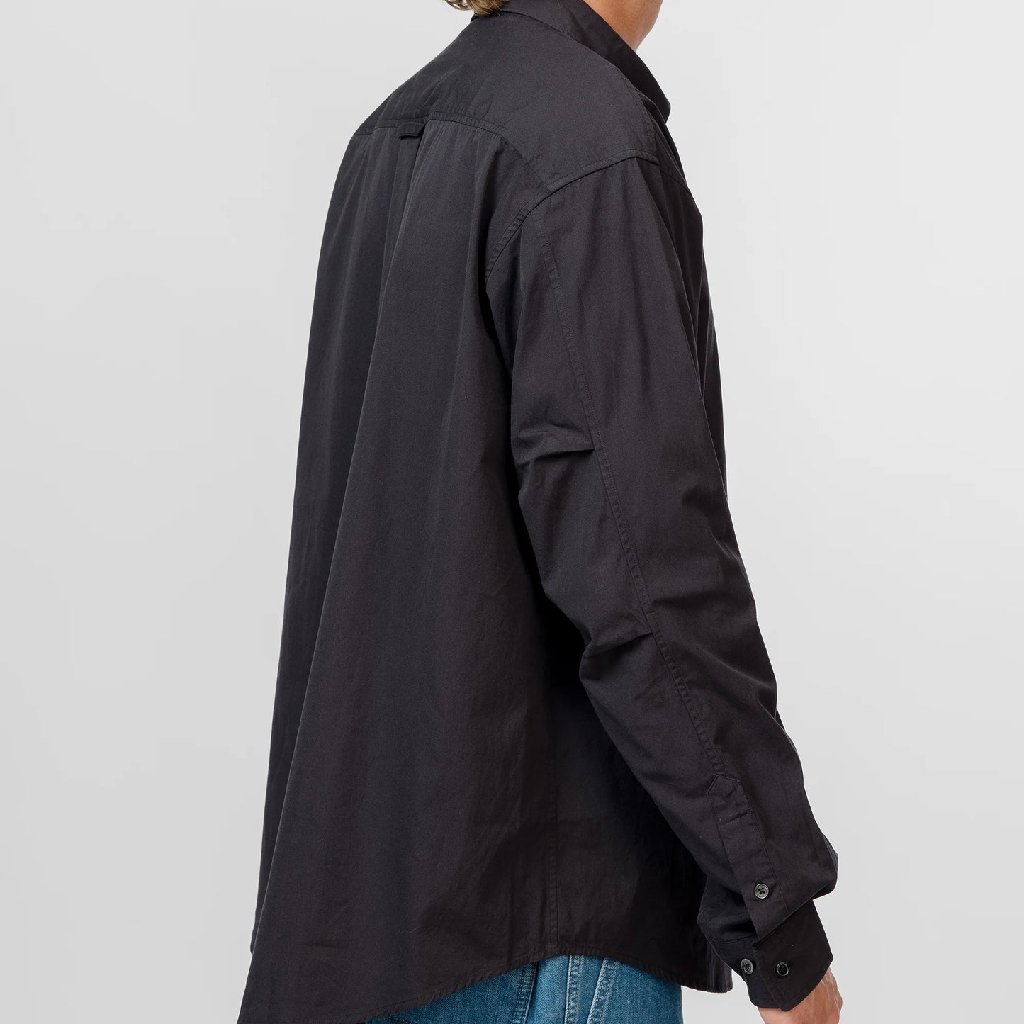 Person wearing a black shirt with rolled-up sleeves on a white background