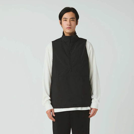 Person wearing a black vest over a white shirt on a plain background