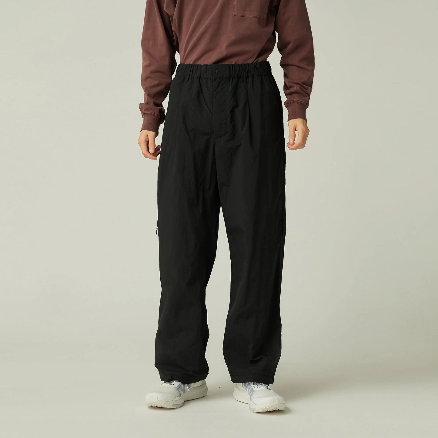 Person wearing a brown sweatshirt and black pants on a plain background